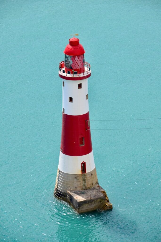 red and white lighthouse beside green wall