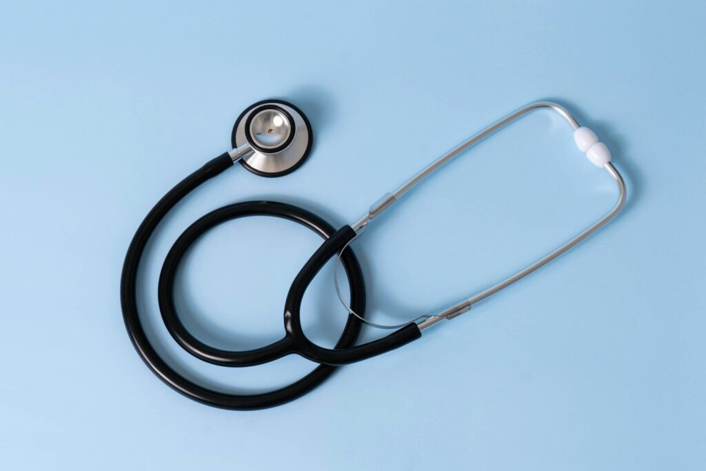 A black medical stethoscope on a light blue background
