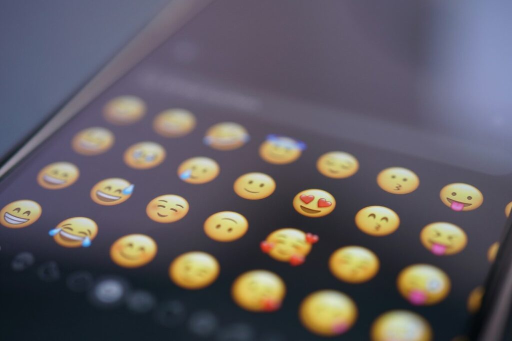 An emoji keyboard is displayed on a phone