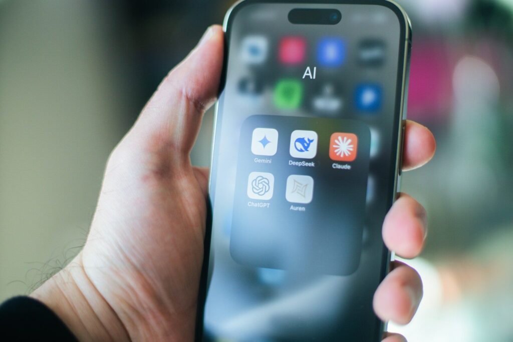 A hand holds a smartphone with various apps